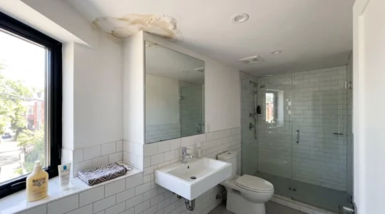 Salle de bain contemporaine avec carrelage blanc et trace d'humidité visible au plafond