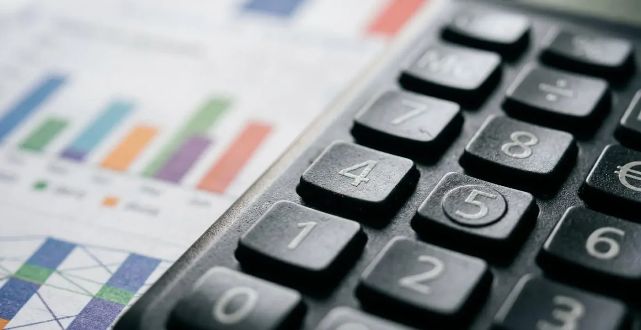 Gros plan sur calculatrice et documents de factures énergétiques illustrant le calcul de rentabilité du chauffage