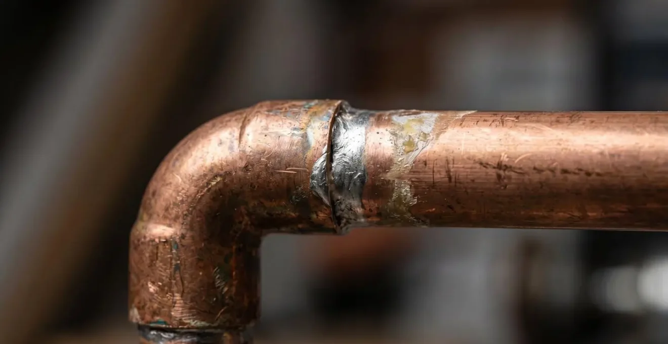Vue macro sur une soudure de tuyau en cuivre montrant les détails de texture et la qualité du travail artisanal en plomberie
