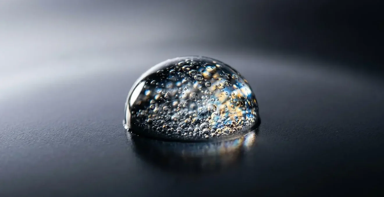 Vue macro d'une goutte d'eau avec liquide vaisselle illustrant l'action des tensioactifs sur les graisses
