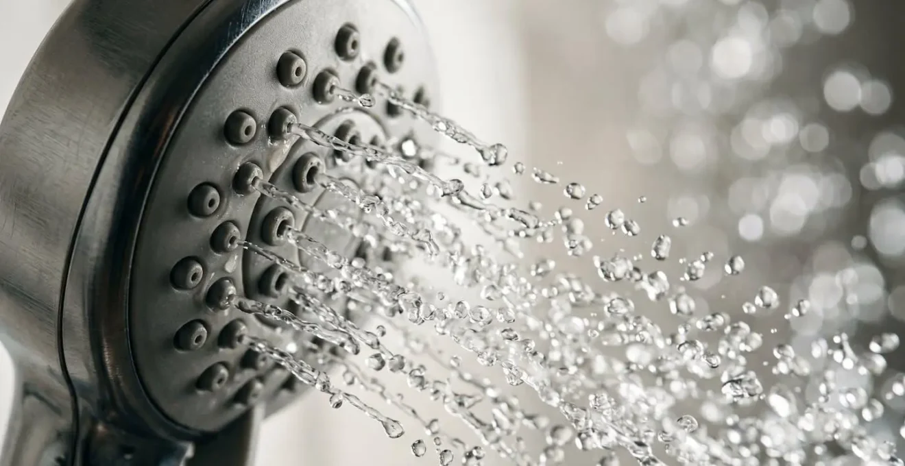Gros plan macro sur la technologie d'aération d'une pomme de douche économique avec jet d'eau en action